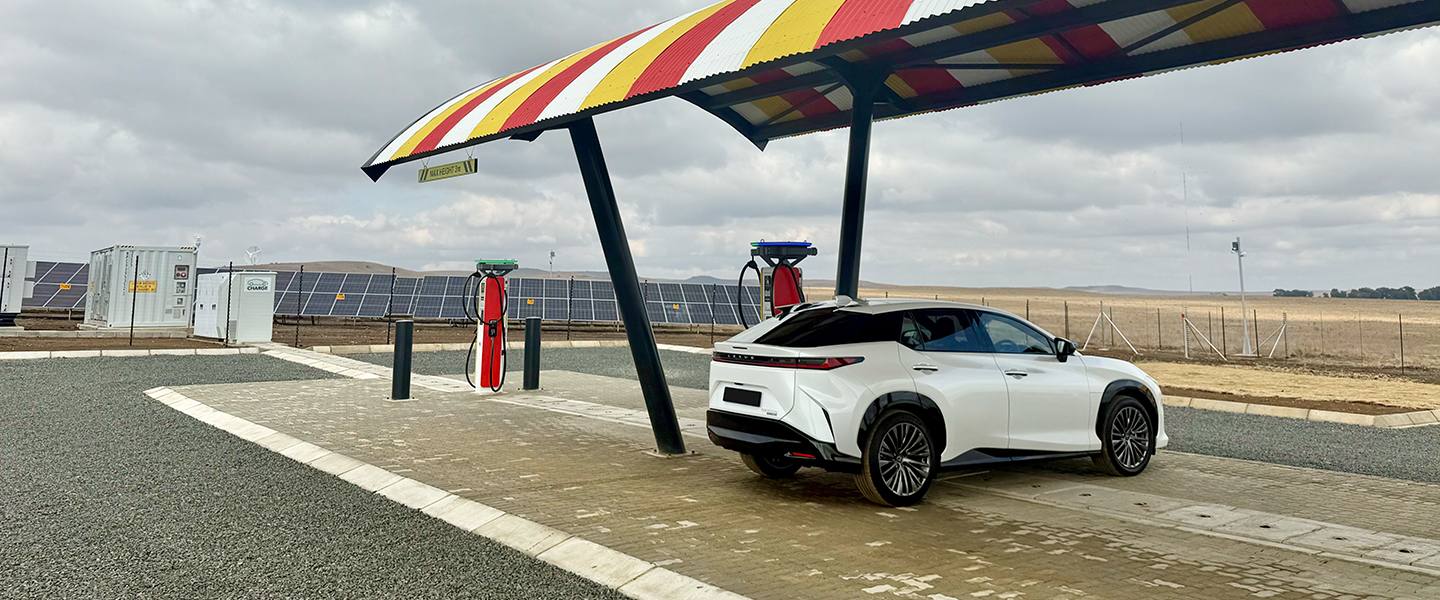 White Lexus RZ parked beneath a striped solar charging canopy