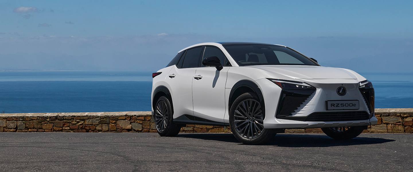 White Lexus RZ parked beside the ocean on a clear day