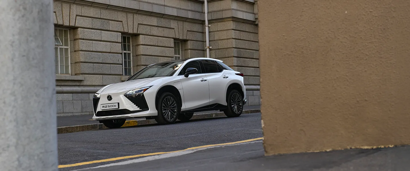 The white Lexus RZ driving on an open road
