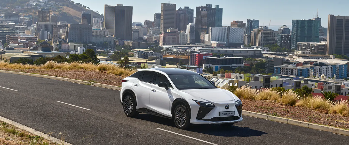 The white Lexus RZ driving through a city street